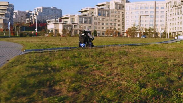 Aerial view of a man living with a disability with amputated legs and arms driving on an electric wheelchair along the brick path in Far Eastern Federal University campus area