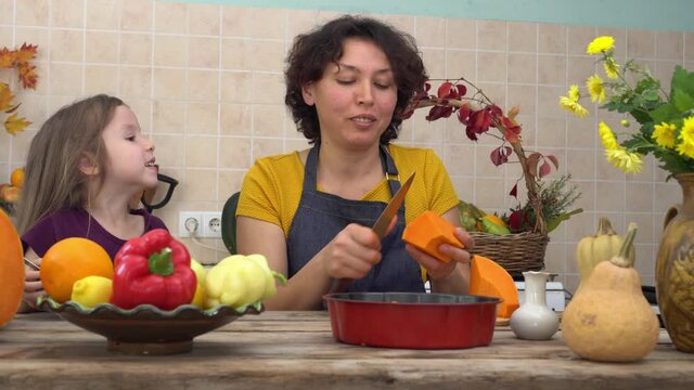 Thanksgiving Holiday Tradition. Happy mother and daughter cook pumpkin pie in the kitchen. Autumn home decoration