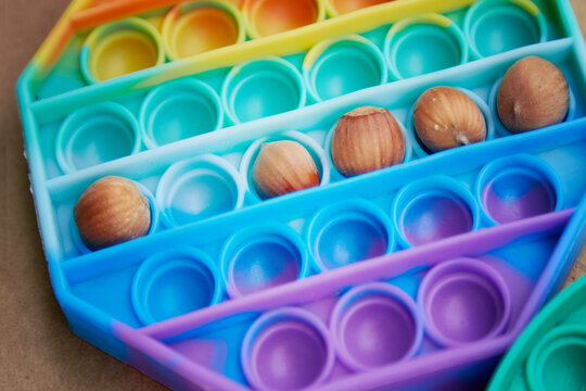 Pop it toy with hazel nuts. Invented games for motor skills development. Rainbow sensory fidget pust it. Top view. Copy space. High quality photo.