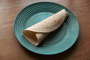 A folded wholegrain wrap on a green plate.