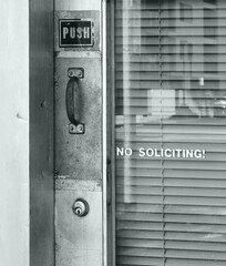 Glass  business door with "push" and "no soliciting" signs. 