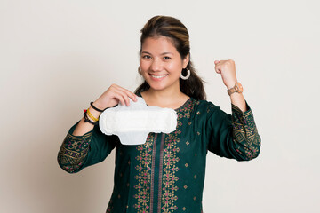 Young indian girl cheering while holding a sanitary pad in her hands and standing on a white isolated background.