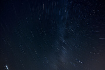 Star trails in the dark night sky. North star top right. Long exposure, motion blurred.