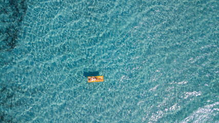 Female tourist enjoy floating on transparent blue sea water laying no a colorful inflatable lilo...