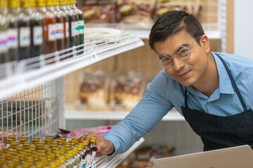 Young male owner use computer laptop to check and trace his stocks and remaining goods in his startup store with care.  Products inventory for small shop. Café owner use application to manage stocks