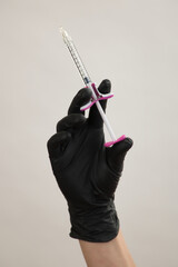 A hand in a black glove holds an injection syringe