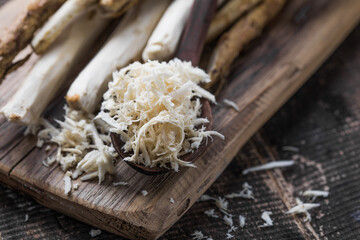 Fresh organic horseradish or Horse-radish root on wooden cutting board.