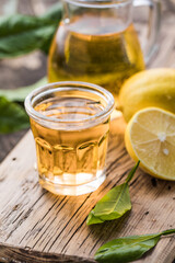 Traditional homemade lemon liqueur limoncello and fresh citrus on a wooden table.