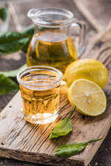 Traditional homemade lemon liqueur limoncello and fresh citrus on a wooden table.