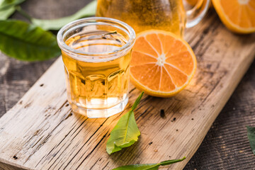 Traditional homemade orange liqueur limoncello and fresh citrus on a wooden table.