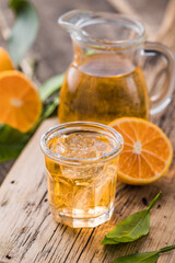 Traditional homemade orange liqueur limoncello and fresh citrus on a wooden table.