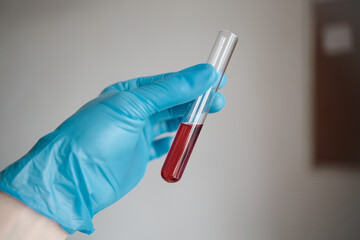 A glass tube with a red reagent, a drug analysis, which is held in the hand on a white background