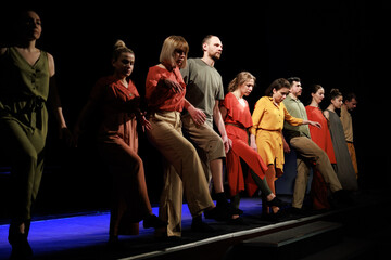 Actors and actresses perform a modern performance on the stage of the theater.