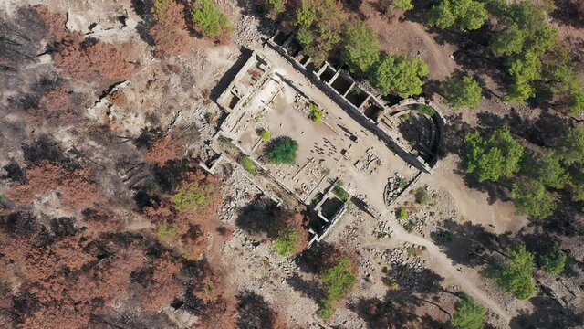 Taurus Mountains. Turkey. Manavgat. Seleucia. Burnt tall pines. Black forest. Charred tree trunks. Drone shooting. Tourists are walking around in the remaining of ancient city Lyrbe at manavgat
