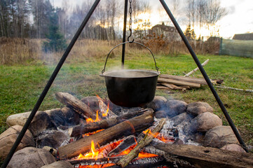 Cauldron on a tripod over the fire. Camping outdoor food preparation