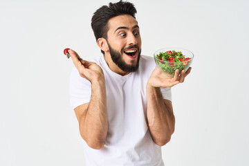 Cheerful man in a white T-shirt with a plate of light green and a healthy meal