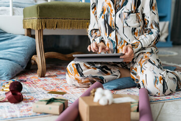 Girl in pajamas is looking for ideas for Christmas gifts on the Internet. Using tablet at home