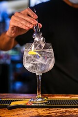 Standing barman prepares gin and tonic on the wooden counter at the pub