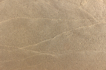 Light brown beach sand texture with crossing line pattern from where ocean waves have left their mark