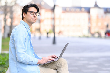 パソコンを持ち遠くを見つめる男性
