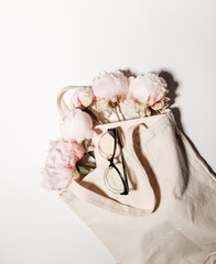 pink peony flowers in a string bag on a white background