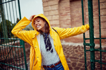 Fototapeta premium A young girl enjoys walking and listening to the music on the rain. Walk, rain, city