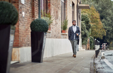 A young elegant and handsome man is walking the city on a cloudy day. Walk, rain, city