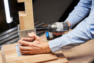 male hands screw the nut to furniture fittings with an automatic wrench