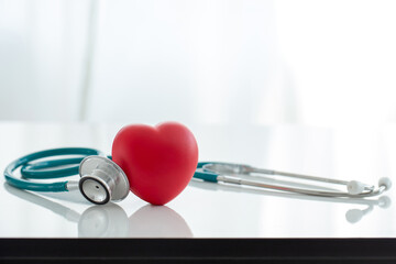 Red heart love shape hand exercise ball with doctor physician's stethoscope on white background:...