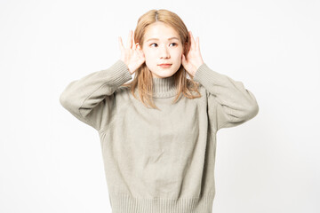 聞き耳を立てて噂を聞くセーターを着た若い女性