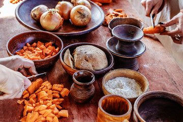 Earthenware with food on a wooden table. The process of preparing a dish from vegetables and bread....