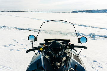 A fragment of a snowmobile against the background of a frozen river. Equipment for traveling in...