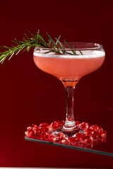 Festive isolated red cocktail. Pomegranate drink with white egg and rosemary