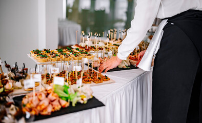 woman hands of a waiter prepare food for a buffet table in a restaurant
