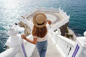 Holiday in Spain. Back view of young traveler woman descends stairs towards the Mediterranean...