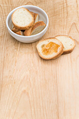 white stoneware bowl with fresh organic sliced bread and jam on a rustic wooden background