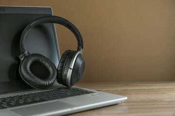 Black headphones on the laptop isolated on the wooden background 