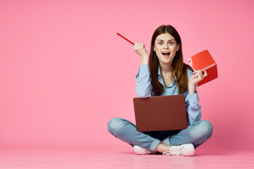 woman sitting on floor with laptop shopping entertainment pink background