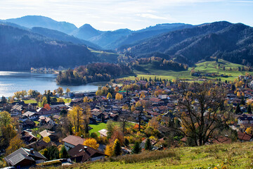 Fototapeta na wymiar Panoramic view of Schliersee lake during Autumn with Alps as a background. Mountain lake Schliersee during Fall and a small city in german Alps, Bavaria, Germany 
