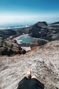 Hiking Woman legs on the mountain top above crater and lake of Gorely volcano, Kamchatka