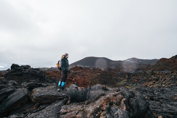 Obraz na płótnie Canvas Traveler female walking on the frozen lava of volcano. Hiking in the mountains of Kamchatka