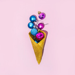 Creative idea of Christmas decoration in an ice cream cone. Festive minimal composition on pink backgrounds. Trendy concept.