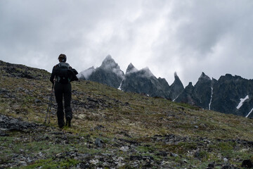 Fototapeta na wymiar Silhouette of hiker female walking in the mountains. Climbing peak, trekking in Kamchatka