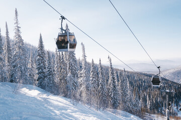 gondola ski lift in mountain ski resort, winter day, snowy spruce forest © Annatamila