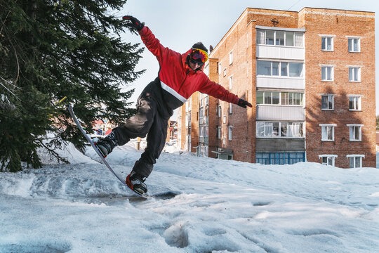 Portrait of snowboarder jumping in city. Urban street snowboarding