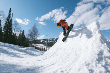 Snowboarder male jumping on quarter pipe snowboard in winter sunny day. Freestyle snowboard training