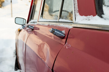 old broken vintage red rusty retro car parked in winter on snow background on frosty winter day
