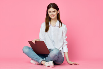 Fototapeta na wymiar woman sitting on floor with laptop shopping entertainment pink background