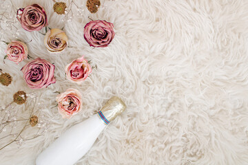 Flowers on soft white fur. Sheep skin and beautiful romantic roses. Celebration flat lay, copy space.