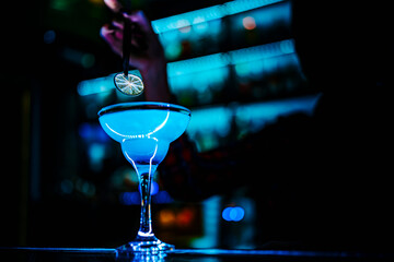 woman bartender hand at the bar or pub to prepare a cocktail Blue Lagoon